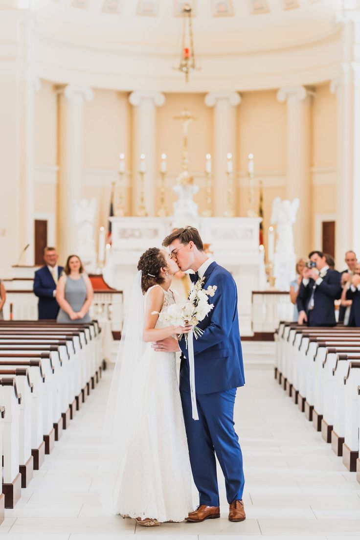 a bride and groom kissing in front of the pews at their wedding ceremony venue