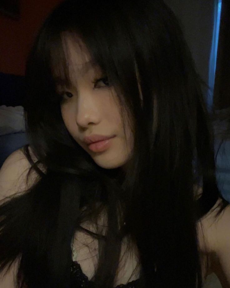 a woman with long black hair is looking at the camera