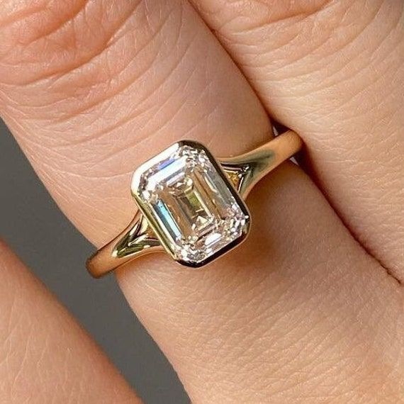 a close up of a person's hand with an engagement ring on their finger