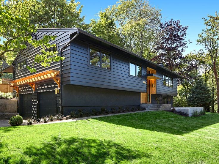 a modern house in the middle of a green yard with trees and grass on both sides