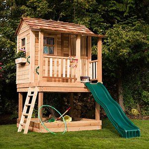 a wooden play house with a slide and climbing frame in the grass next to it