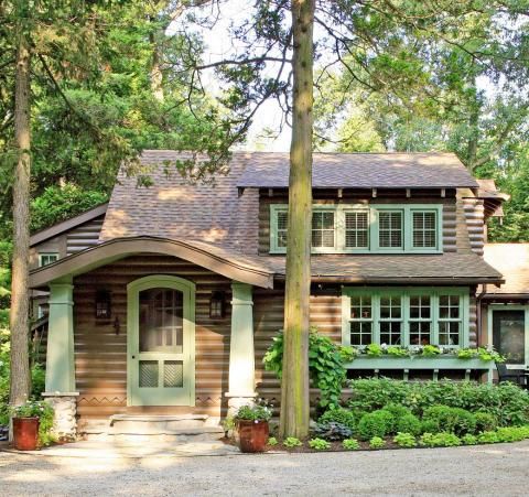 a house in the woods with lots of greenery on it's front lawn