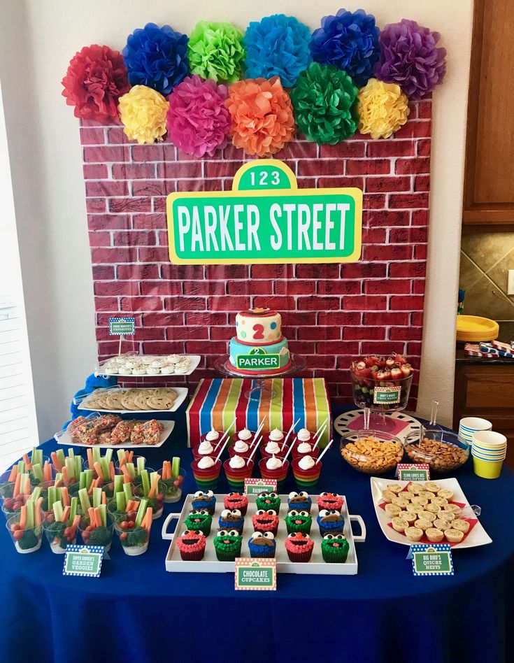 a table topped with lots of desserts next to a brick wall covered in paper flowers