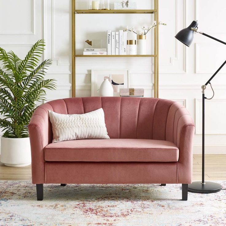 a living room with a pink couch, lamp and bookshelf