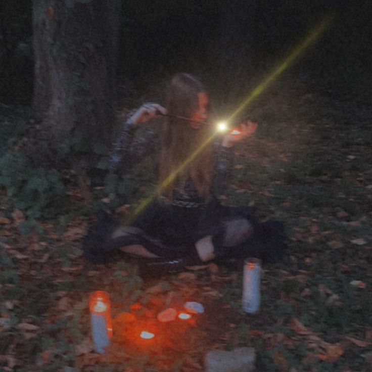 a woman sitting on the ground with some candles in front of her and one light shining