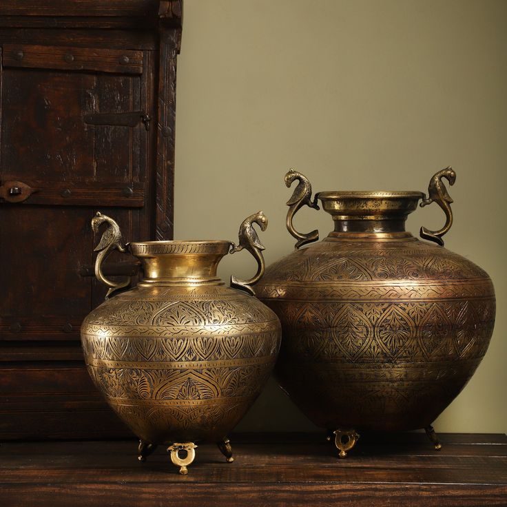 two large vases sitting on top of a wooden table next to each other in front of a dresser