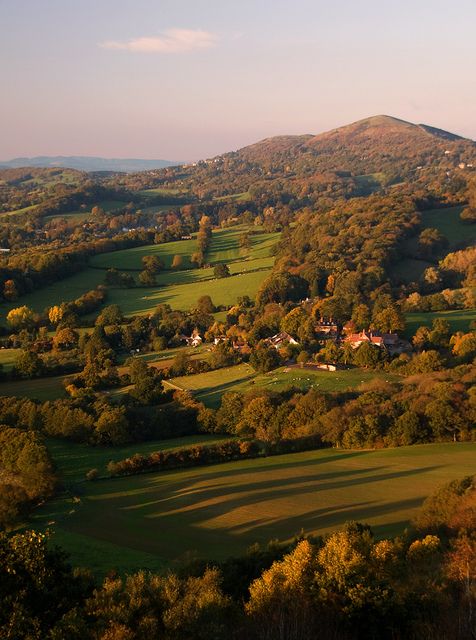 an aerial view of the rolling hills and valleys in autumntime, with houses on the hillside