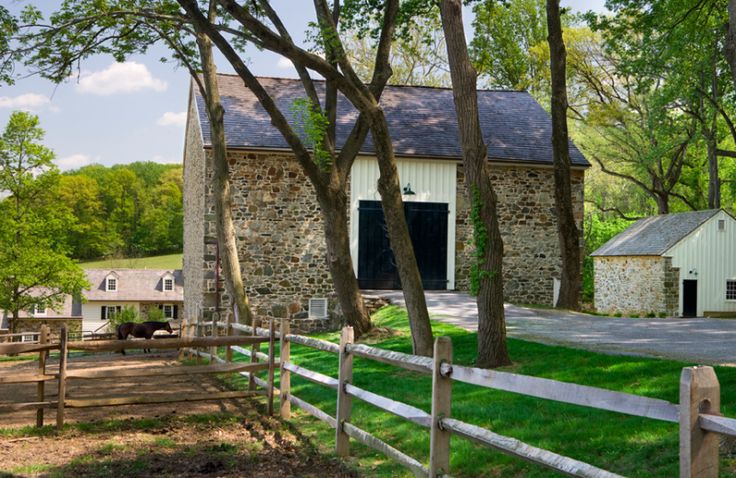 an old stone building with a horse in the yard next to it and trees on either side