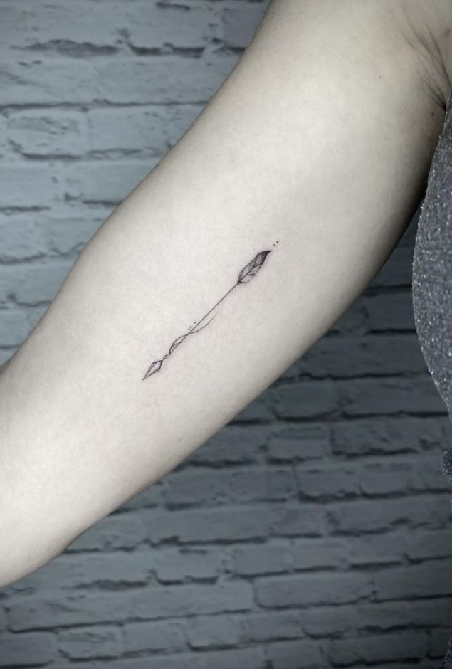 a woman's arm with an arrow tattoo on the left side of her arm