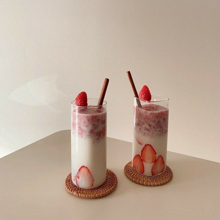 two glasses with strawberries in them on a table