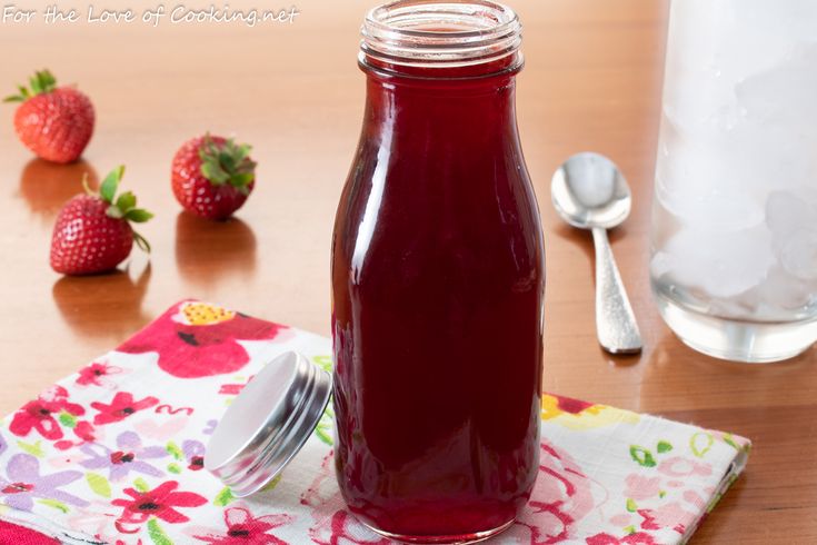 a glass jar filled with liquid sitting on top of a table next to spoons