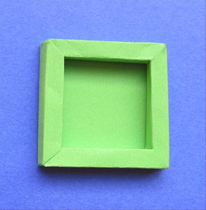 a green square shaped object sitting on top of a blue surface with the bottom half cut out