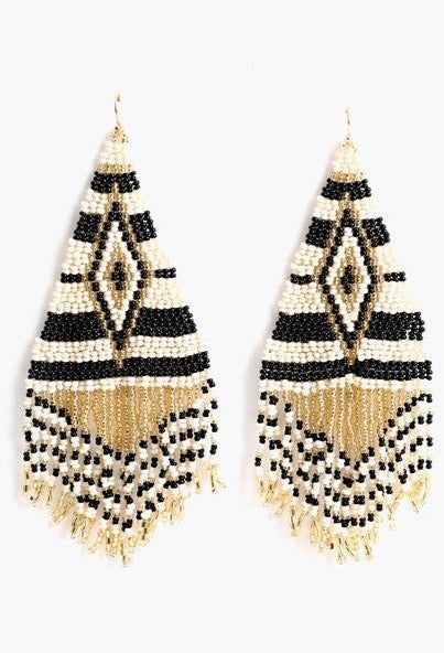 These Parvati Earrings feature an artistic geometric pattern that is hand beaded and made in India. Exuding elegance, the black, gold, and white tribal design is crafted with superior quality. Add a touch of sophistication to any ensemble with these stunning earrings. Bohemian White Earrings With Black Beads, White Bohemian Beaded Earrings With Black Beads, Traditional White Earrings With Gold Beads, Bohemian White Beaded Earrings, White Bohemian Geometric Earrings, White Geometric Bohemian Earrings, Bohemian White Geometric Earrings, Elegant White Beaded Earrings For Festivals, Geometric Beaded Gold Earrings