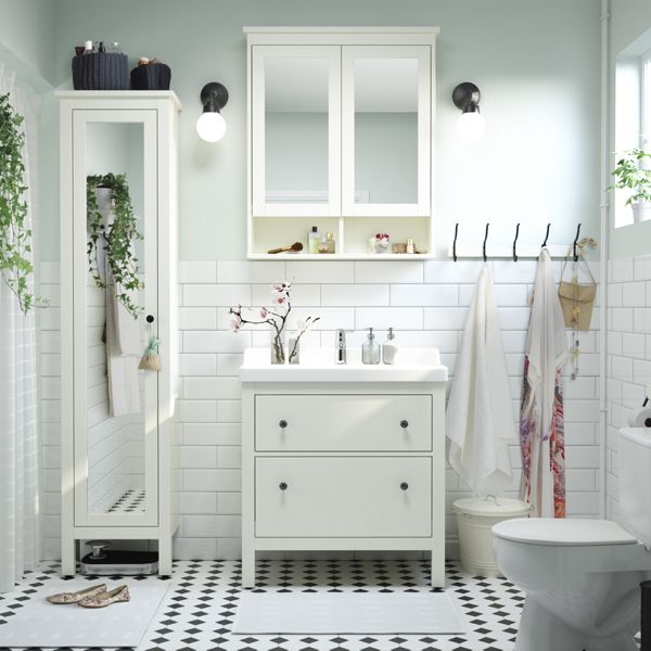 a bathroom with white tiles and green plants on the wall, along with other accessories