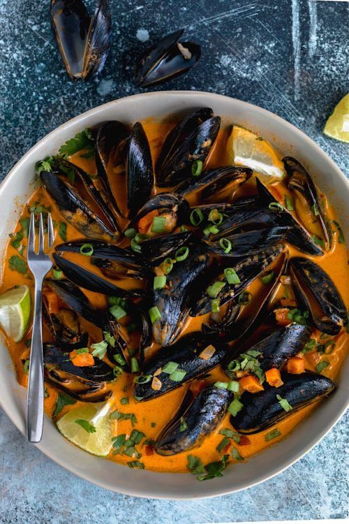 a white bowl filled with mussels and garnish