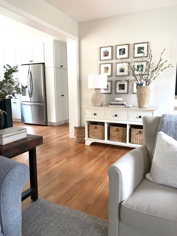 a living room with white furniture and pictures on the wall above it's coffee table