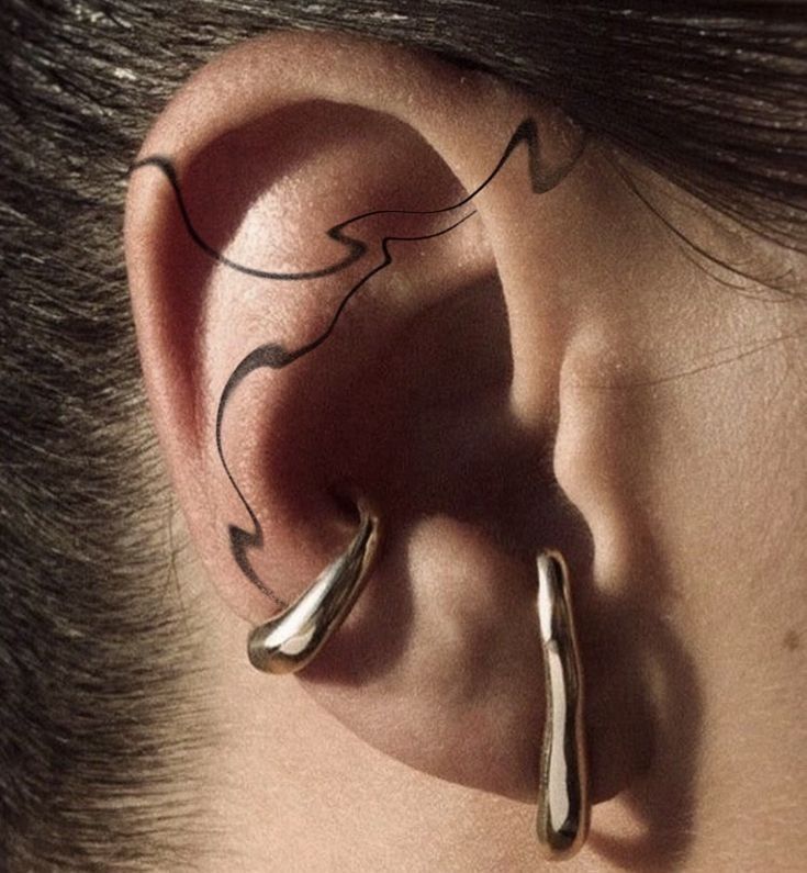 a woman's ear is shown with tattoos on it