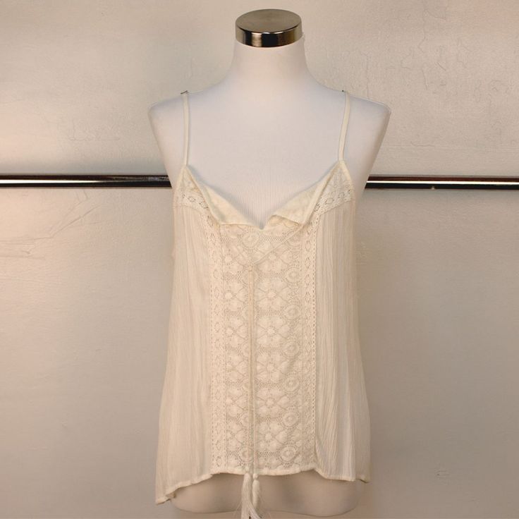 This Pretty Camisole Tank To Top Features Lace Detailing On The Front And Back. Tie Front With Tassels And Spaghetti Straps. White Tank Camisole With Delicate Straps, White Tank Strap Tops For Beach, White Sleeveless Camisole With Delicate Straps, White Beach Camisole With Built-in Bra, White Camisole With Delicate Straps For Vacation, White Tops With Adjustable Straps For Vacation, White Delicate Straps Camisole For Vacation, Beach Camisole With Straps, Delicate Straps Tank Top For Vacation