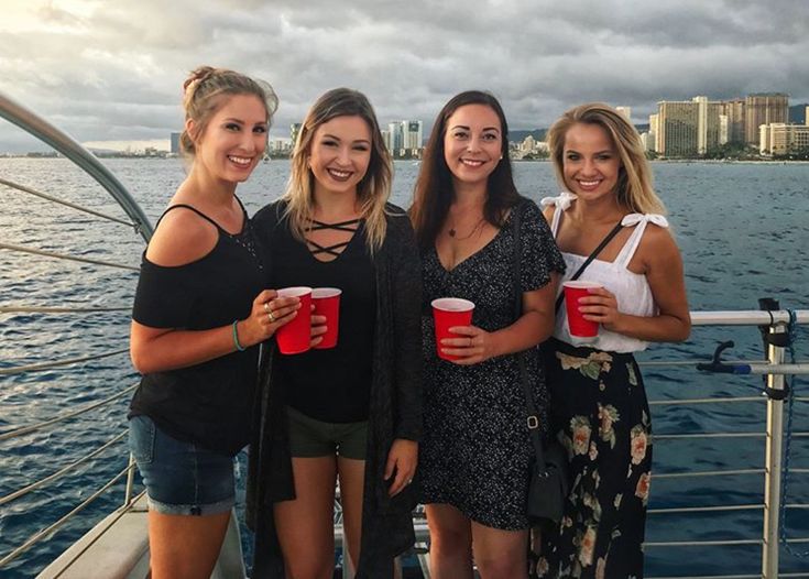 three women standing on a boat holding red cups