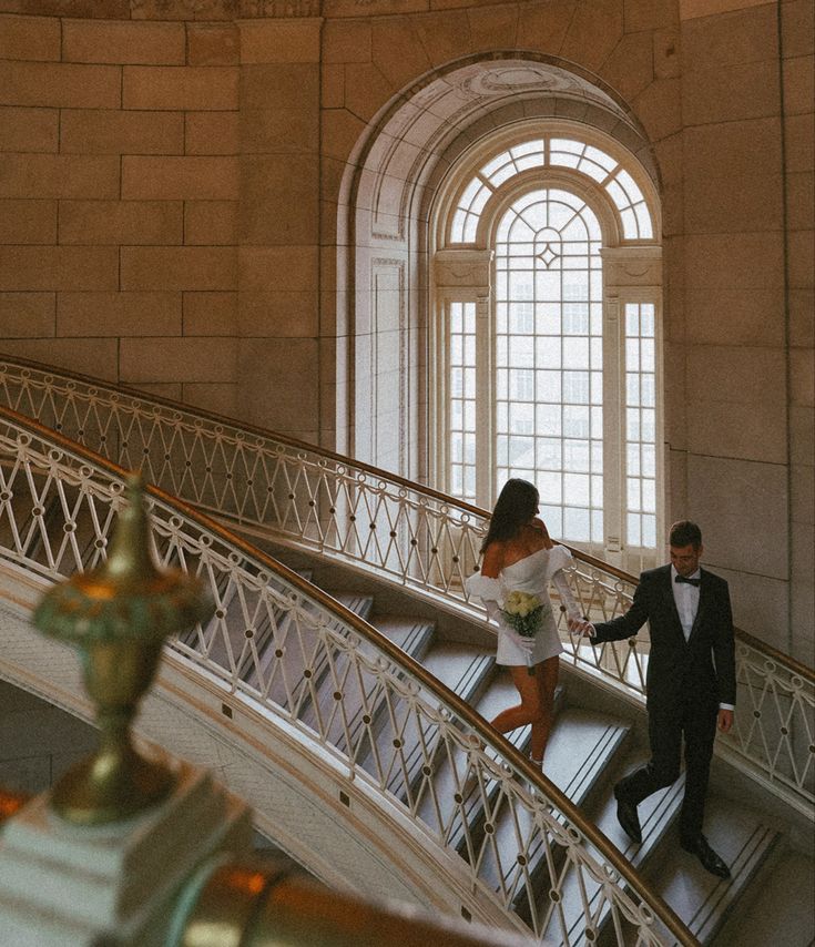 a bride and groom are walking down the stairs in an old building with stained glass windows