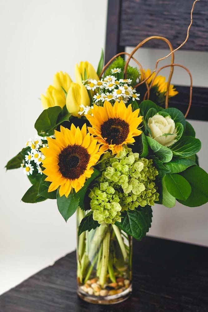 a vase with sunflowers and other flowers on a table