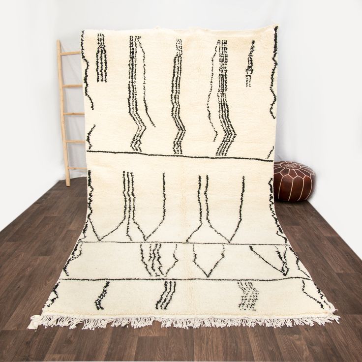 a white rug with black lines and fringes on the floor next to a chair