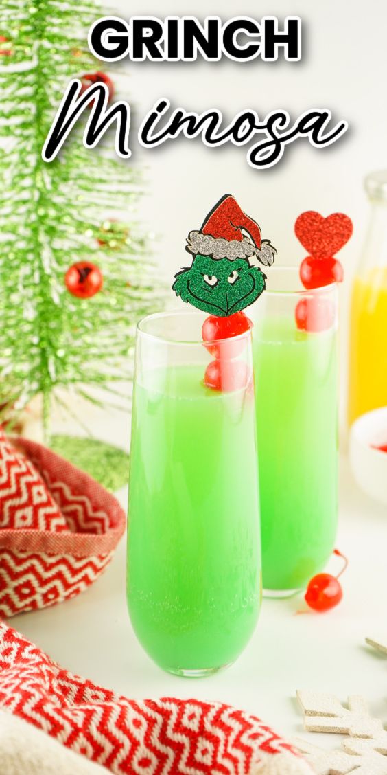 two glasses filled with green liquid next to a christmas tree and candy canes on the table