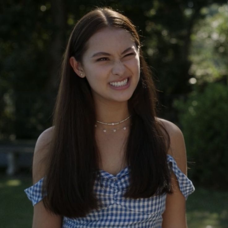 a woman with long hair wearing a blue gingham top smiling at the camera