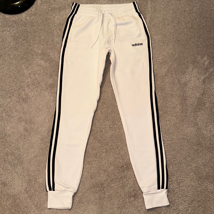 Brand New, Never Been Worn Features Pockets, The Iconic 3 Strips On Both Sides Of The Legs, And A Drawstring. White Pants With Three Stripes, White Lounge Pants With Three Stripes, White Three-stripe Pants For Loungewear, White Three Stripes Pants For Loungewear, Sporty White Sweatpants With Side Stripes, White Side Stripes Joggers For Streetwear, White Fitted Joggers For Streetwear, Adidas White Three Stripes Sweatpants, Sporty White Joggers With Three Stripes Branding