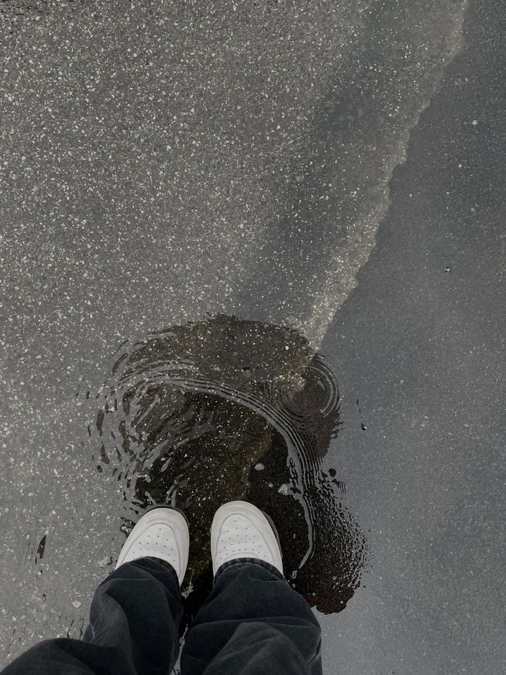 a person standing in the middle of a puddle with their feet up and legs down