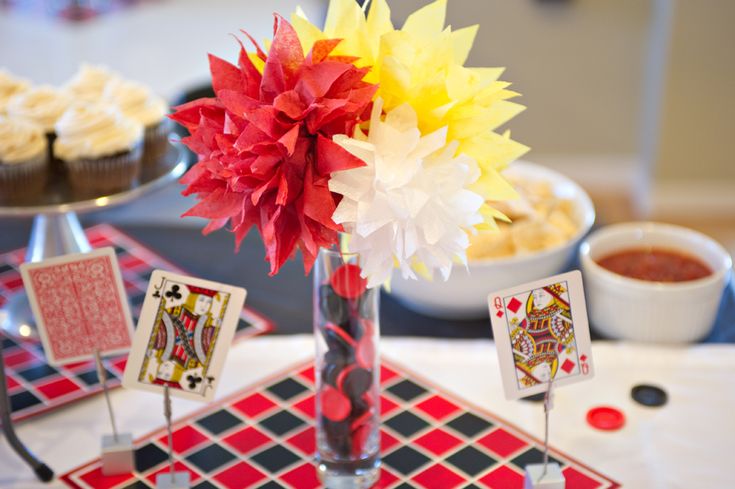 a table topped with cupcakes, cards and a vase filled with flowers