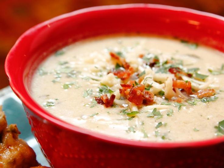 a red bowl filled with soup next to some fried food