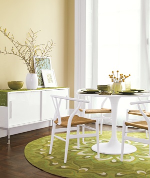 a table and chairs in a room with green rugs on the hardwood flooring