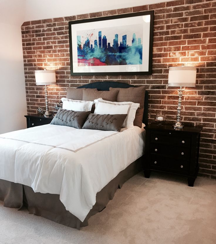 a bedroom with brick walls and white bedding, two lamps on either side of the bed