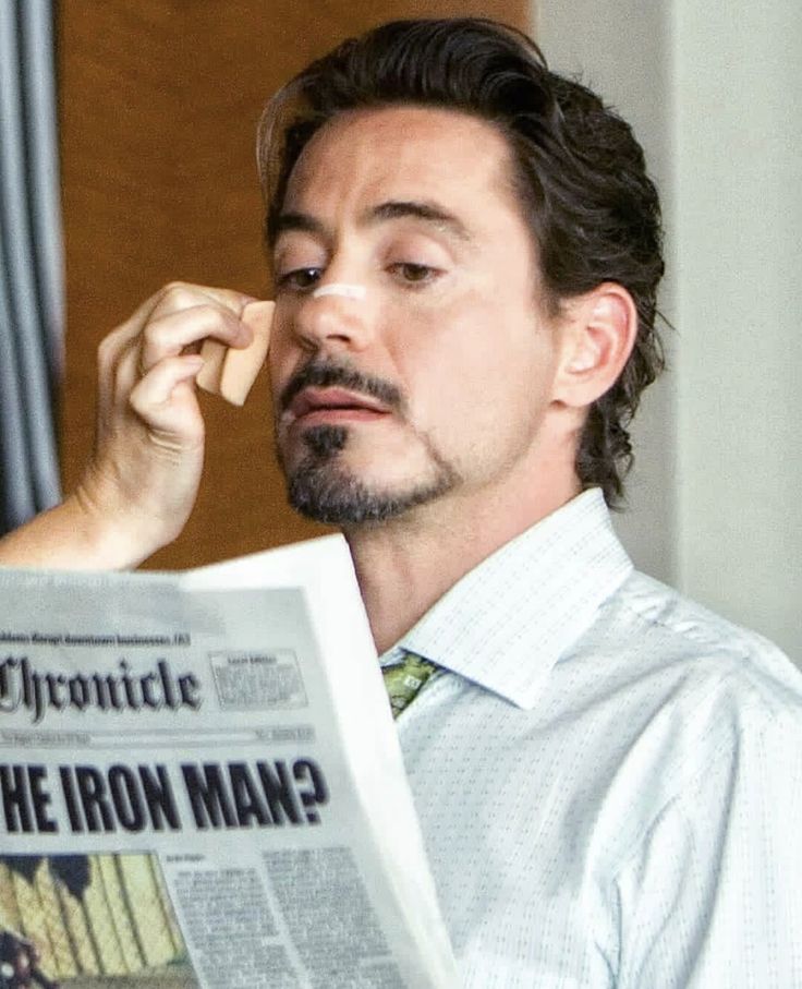 the man is reading the paper while holding his nose