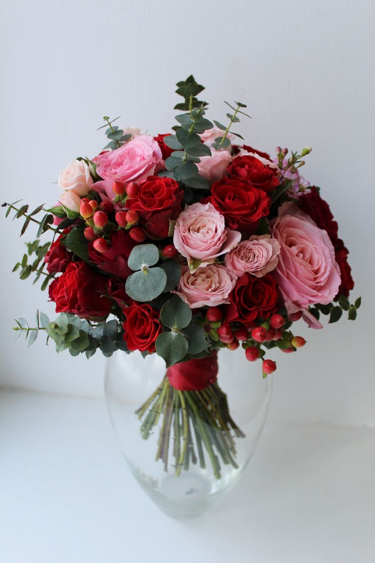 a vase filled with lots of red and pink flowers