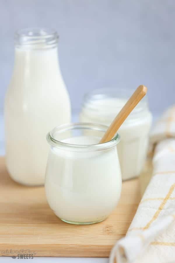 three jars filled with milk sitting on top of a wooden cutting board