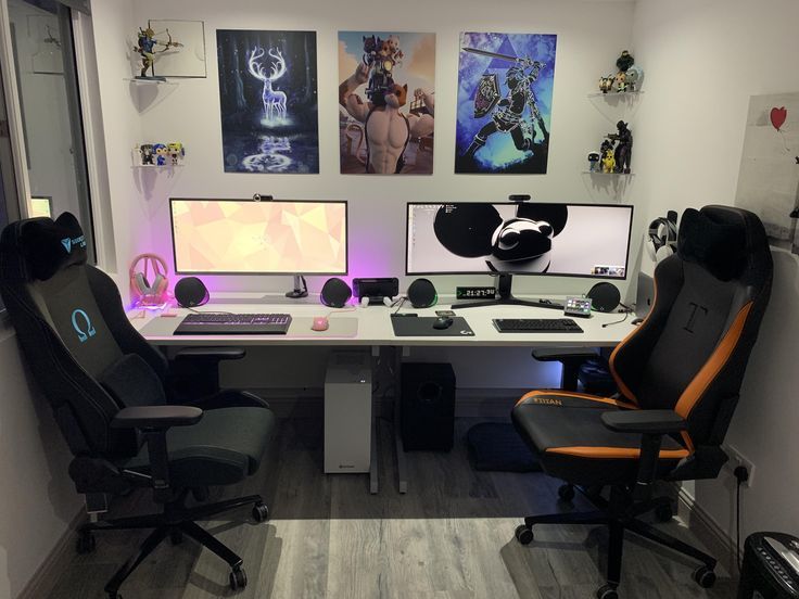 two computer monitors sitting on top of a desk next to each other in front of pictures