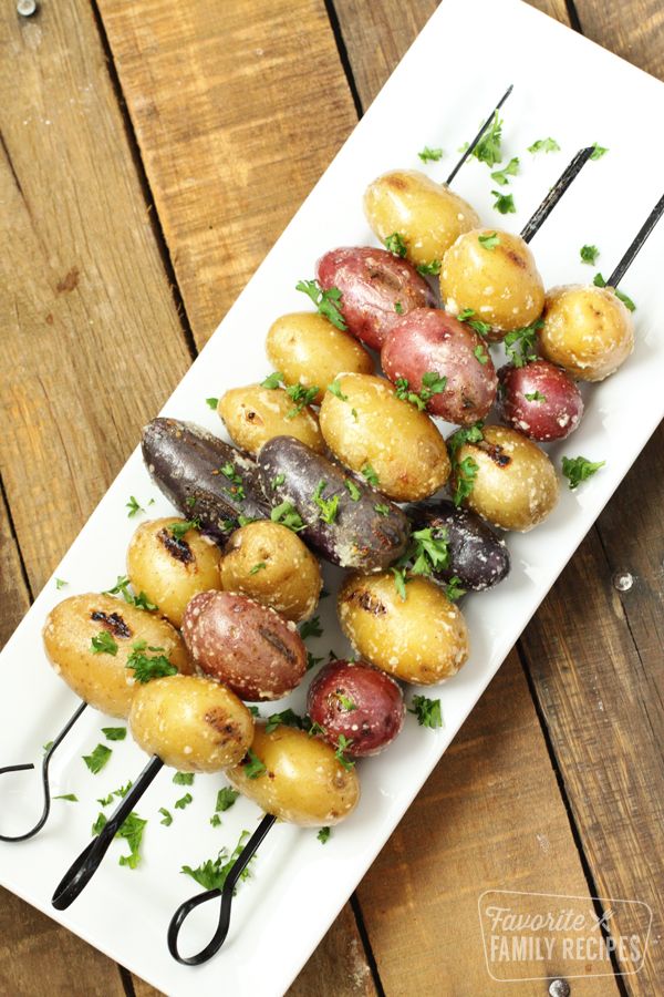 grilled potatoes on skewers with parsley garnish served on a white plate