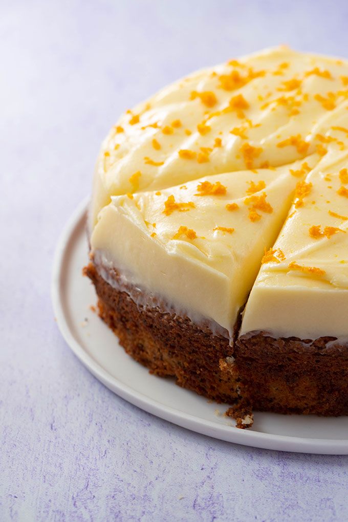 a cake with white frosting and orange sprinkles sitting on a plate