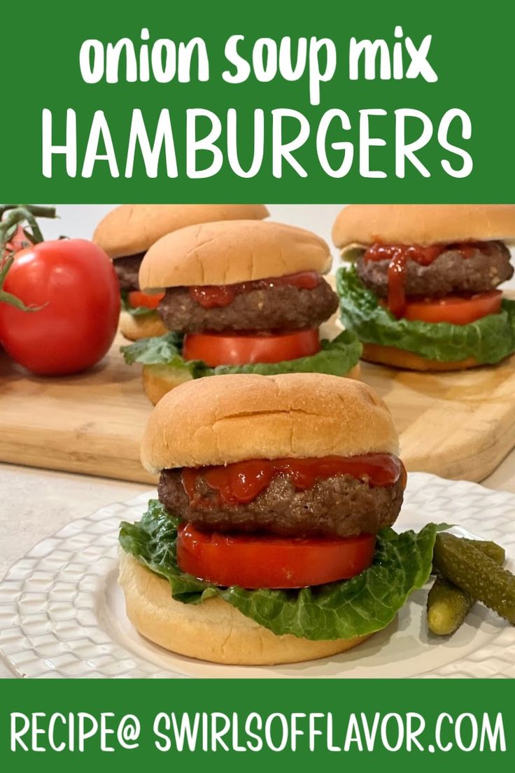 three hamburgers with tomatoes and lettuce on them, sitting on a cutting board