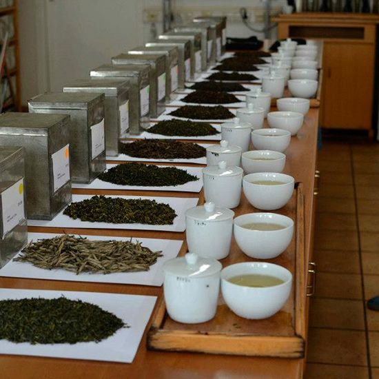 there are many cups and bowls on the table with teas lined up next to each other