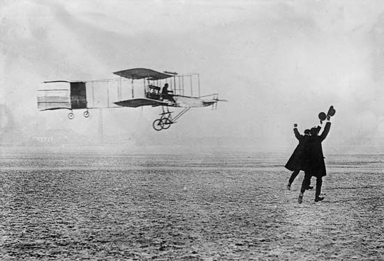 an old photo of a man flying a plane in the sky with two people on it