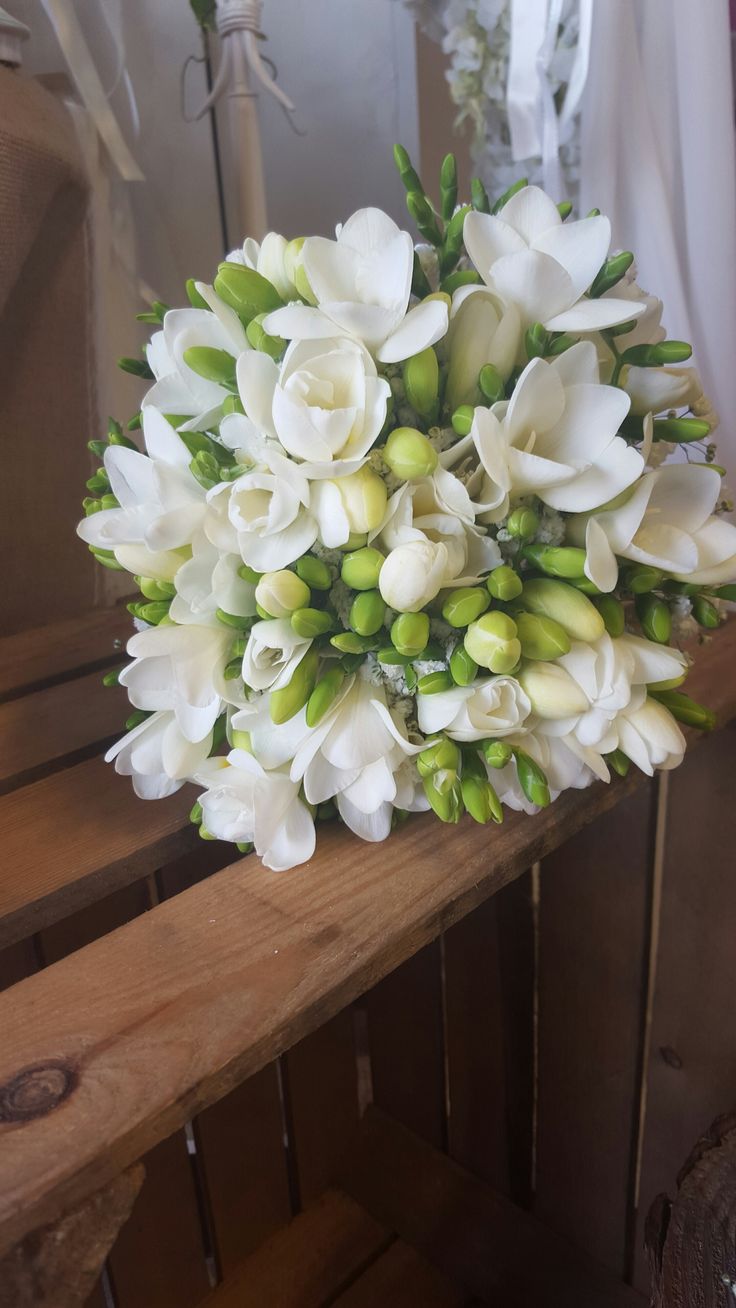 a bouquet of white flowers sitting on top of a wooden bench