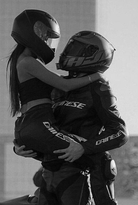 two people hugging each other while wearing helmets