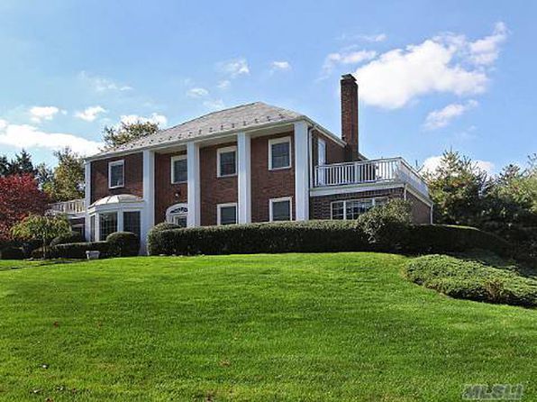 a large brick house sitting on top of a lush green field