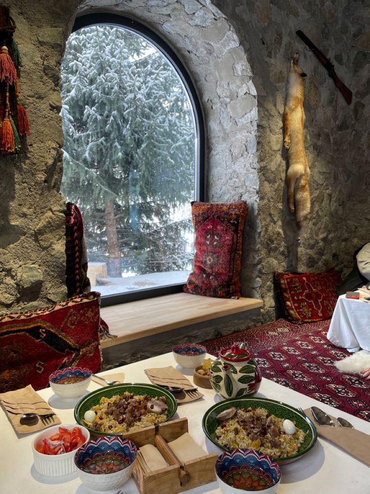 a table topped with plates of food next to a window filled with snow covered trees