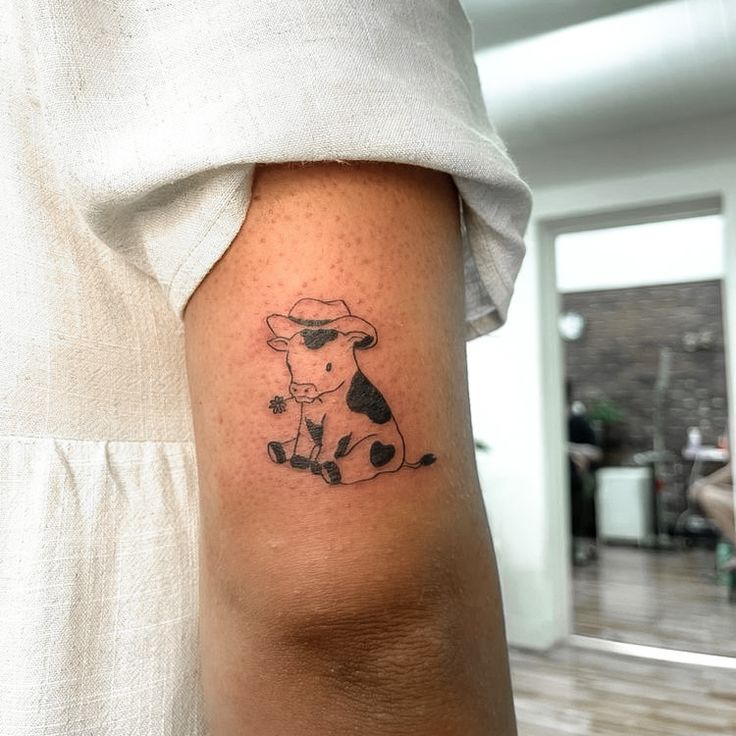 a small cow tattoo on the arm