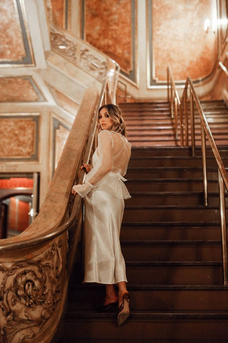 a woman is standing on the stairs in a white dress