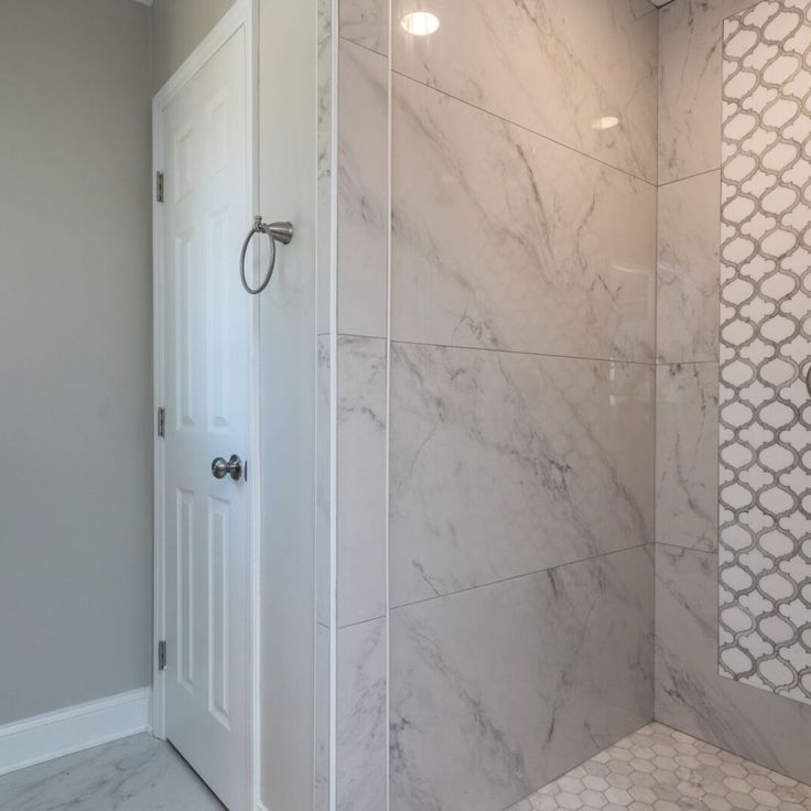 a bathroom with marble walls and flooring next to a white door in the shower